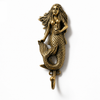 Brass mermaid single wall hook isolated on white background showing full sculptural mermaid figure, intricate detail, flowing hair, scaled tail and warm gold brass finish. Handcrafted coastal nautical decorative key hook and towel hook for beach house decor, coastal bathroom and housewarming gift for mermaid collectors