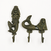 Brass mermaid wall hook set in antique finish on white background showing double hook mermaid and single hook mermaid with rich aged dark brass patina and intricate sculptural detail. Handcrafted coastal nautical decorative coat hook and towel hook set for rustic beach house decor and housewarming gift