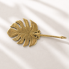 Flat lay of brass monstera leaf wall hook in gold finish, decorative tropical wall hook
