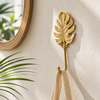 Brass monstera leaf wall hook used as a bathroom towel hook, tropical botanical wall decor in gold finish