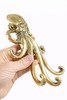 Side view of brass octopus wall hook in hand kraken hardware detail