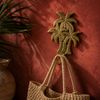 Brass palm tree wall hook polished gold finish mounted on rich terracotta red wall holding two woven rattan beach bags with tropical palm leaves – palm tree coat hook key hook – tropical boho beach house entryway decor – housewarming gift – handcrafted solid brass made in Bali by UbudGlassandBrass