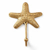 Brass pebbled starfish wall hook on a white background, with a bumpy sea star surface, rounded arms and a long stem ending in a ball-tipped hook. Handmade cast brass starfish towel and coat hook, hand-finished by artisans in Ubud, Bali.
