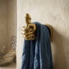 Brass penis hand wall hook mounted on rustic textured wall holding blue denim towel – funny adult bathroom after dark decor – quirky kinky home decor – man cave bachelorette bachelor housewarming gift – polished gold brass hand-cast – handcrafted in Bali UbudGlassandBrass