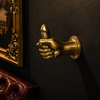 Brass penis hand wall hook in dark moody room with ornate gold frame and leather chair – after dark dungeon kinky adult decor – gothic maximalist quirky home decor – funny adult gift man cave bachelorette bachelor party – polished gold brass hand-cast – made in Bali