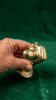 Portrait view of hand holding brass penis hand wall hook against green velvet showing complete hand sculpture gold finish and hook detail – funny adult after dark dungeon quirky kinky decor – man cave bachelorette housewarming white elephant gift – polished gold brass Bali