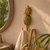 Brass pineapple double wall hook polished gold in tropical bathroom holding linen towel beside round mirror with plants – pineapple wall hook towel hook coat hook – tropical boho beach house coastal home decor – housewarming gift – handcrafted solid brass made in Bali