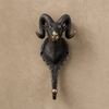 Gold and antique brass ram wall hooks mounted side by side on a beige wall showing both finish options — solid brass sculptural wall hook handmade in Bali