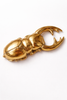 Brass scarab beetle bottle opener on white background, sculptural bar tool