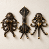 Set of three brass sea creature wall hooks in a dark aged patina finish on a grey background