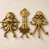 Set of three brass sea creature wall hooks in a dark aged patina finish on a grey background
