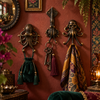 Set of brass octopus, squid, and skull-octopus hooks mounted on a deep red wall holding bags and scarves, with flowers nearby