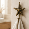 Brass sea star wall hook holding a folded towel in a bathroom