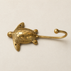 Side view of a brass sea turtle wall hook showing the curved hook shape and engraved shell texture, from the turtle hook set.