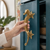 Hand opening blue door using brass seahorse door pull, coastal entry hardware