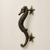 Brass seahorse door handle on cream background, vintage bronze finish