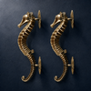 Set of two gold brass seahorse door pulls on dark navy background, double door hardware