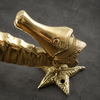 Detailed close-up of gold brass seahorse door handle showing starfish base and casting texture
