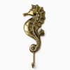 Full length solid brass seahorse wall hook on a clean white background showing complete sculptural seahorse body individual scales fins curved tail and single hook — coastal nautical wall hook handmade in Ubud Bali
