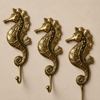 Set of 4 solid brass seahorse wall hooks displayed on a neutral background showing complete coastal hook set with full seahorse sculpting scale detail and hooks — nautical beach house decor handmade in Ubud Bali