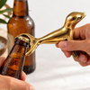 Hand using the brass seal bottle opener to open a brown beer bottle, showing how the seal-shaped bar key lifts a crown cap. A practical beer bottle opener and fun beer lover gift, handmade in Bali.