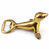 Brass seal bottle opener on a white background, a polished gold brass seal resting on its belly with a bottle-opening loop at its tail. Handmade animal bottle opener and bartender gift, hand-cast in Bali.