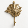 Brass seashell wall hook with spiral web design on a dark grey background, coastal nautical coat hook