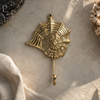 Brass seashell wall hook with spiral web design mounted on a stone textured wall, holding linen fabric, coastal decor