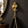Brass shell spiral hook mounted on a dark wall holding a purple towel, close up view