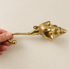 Hand holding a brass shell spiral hook, showing full length and curved hook end