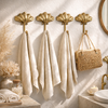 Set of four brass seashell wall hooks mounted in beach house bathroom