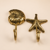 Brass shell and sea star wall hook duo on dark background