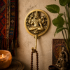 Solid brass meditating Lord Shiva wall hook mounted on a warm textured wall with colorful Indian tapestry mala beads candlelight and brass deity figurine below — Hindu home decor om wall hook ethically handmade by Balinese Hindu artisans in Ubud Bali spiritual yoga room decor