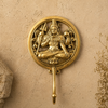 Solid brass meditating Lord Shiva wall hook on a neutral stone background showing full circular relief disc with Shiva in meditation pose and single curved hook below — Hindu god brass hook spiritual home decor handmade in Ubud Bali