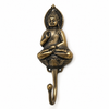 Antique brass sitting buddha wall hook on grey background showing rich dark aged patina finish, meditation posture sculpture, stacked pagoda crown and hook arm. Handcrafted spiritual coat hook, towel hook and key hook for yoga room decor, meditation decor, wabi sabi home decor, zen decor and housewarming gift. Made by professional artisans in Bali. Available in gold finish too.