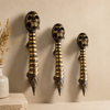 Two solid brass skull spine door handles showing gold and dark antique finish comparison on a neutral wall — gothic double door pull available in two finishes handmade in Bali