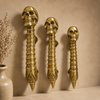 Three solid brass skull spine door handles showing small medium and large size options styled with dried pampas grass — gothic skeleton door handle pair handmade in Ubud Bali