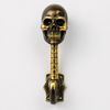 Full length solid brass skull wall hook in dark antique finish on white background showing complete skeleton figure from skull crown to curved hook tip — gothic skull towel hook handmade in Ubud Bali
