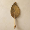Brass Spade Leaf wall hook mounted on a neutral wall, hand-cast botanical hook with natural leaf vein detail.