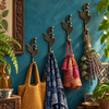 Set of four brass sprout leaf hooks mounted on a teal wall holding a scarf, woven bag, and dried lavender bundle
