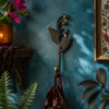 Brass sprout leaf hook mounted on a deep teal wall with flowers and greenery nearby
