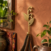 Brass sprout leaf hook mounted on a terracotta wall holding a woven tapestry bag, boho home decor