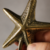 Close-up of handcrafted brass starfish hook showing textured detail