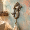 Brass starfish mermaid wall hook mounted on a textured wall, boho coastal jewelry and towel hanger.