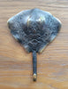 Brass stingray wall hook with a blue-gray patina finish laid on wood, antique-style piece from the nautical coat hook set.