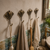 Set of 4 brass stingray wall hooks mounted on a tiled bathroom wall holding towels, handmade nautical coat hook set and coastal decor.