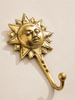 Angled front view of polished gold brass sun wall hook mounted on warm neutral wall showing full hook body and sun face detail – part of celestial brass wall hook set of 3 – boho witchy celestial entryway decor – key hook jewelry holder – astrology housewarming gift – solid brass Bali