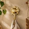 Gold brass sun wall hook mounted on textured beige wall with hanging towels and plant – boho entryway decor