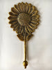 Close-up of brass sunflower hook head and petals, warm golden floral wall decor detail.