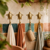 Four brass sea turtle wall hooks mounted in a row on a colorful tiled wall, holding towels as coastal bathroom coat hook set decor.